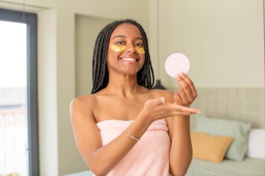 Siyah afro kadın neşeyle gülümsüyor, mutlu hissediyor ve bir konsept gösteriyor. güzellik konsepti