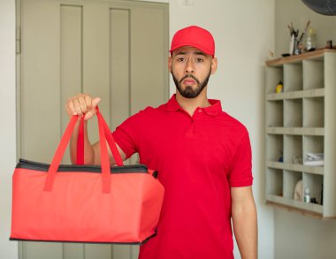 Genç bir adam üzgün ve mızmızlanıyor. Mutsuz bir bakışı var ve ağlıyor. Pizza teslimatçısı konsepti