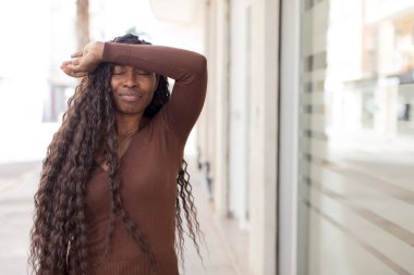 Afro güzel siyah kadın stresli, yorgun ve hayal kırıklığına uğramış görünüyor, alnından ter akıyor, umutsuz ve bitkin hissediyor.