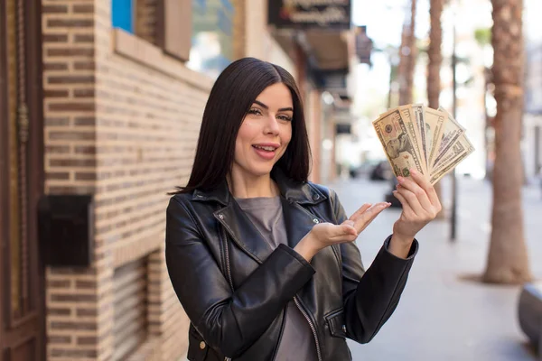 stock image pretty young woman smiling cheerfully, feeling happy and showing a concept. dollar banknotes concept