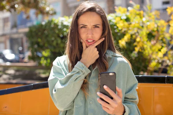 pretty woman with mouth and eyes wide open and hand on chin. smartphone concept