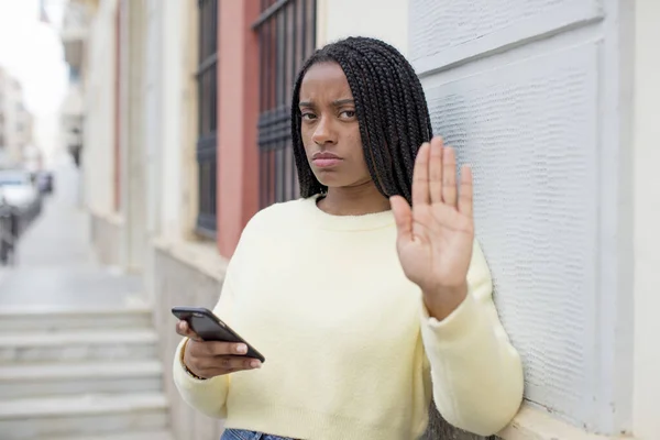 黒いアフロの女が真剣にヤシの実を見せてる スマートフォンのコンセプトを使って — ストック写真