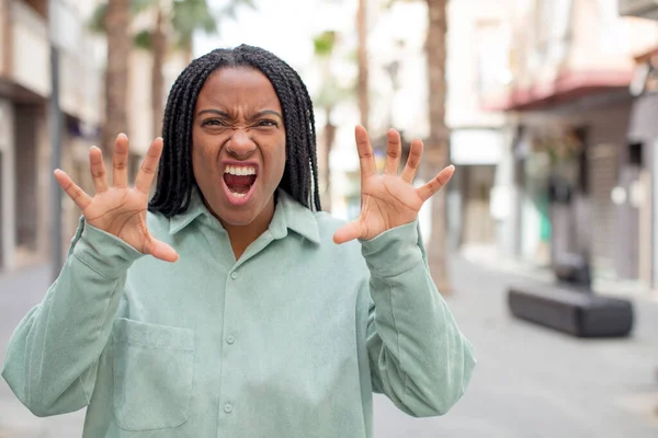 afro pretty black woman screaming in panic or anger, shocked, terrified or furious, with hands next to head