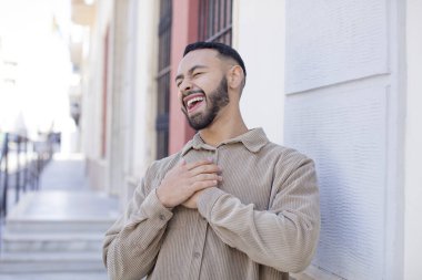 Genç yakışıklı adam komik bir şakaya yüksek sesle gülüyor, mutlu ve neşeli hissediyor, eğleniyor.