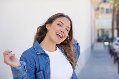 Güzel İspanyol kadın gülümsüyor, kaygısız hissediyor, rahat ve mutlu, dans ediyor ve müzik dinliyor, bir partide eğleniyor.