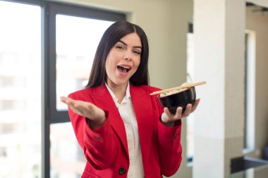 Güzel genç bir bayan mutlu bir şekilde gülümsüyor ve bir konsept sunuyor ya da gösteriyor. Japon ramen kasesi konsepti