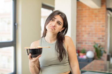 Genç bir kadın üzgün ve mızmızlanıyor. Mutsuz bir bakışı var ve ağlıyor. ramen kasesi