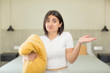 Genç bir kadın omuz silkiyor, kafası karışık ve kararsız. gece kıyafeti konsepti