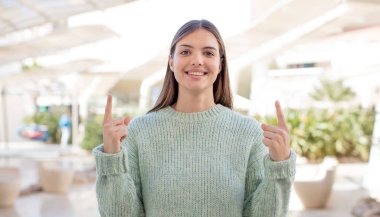 Genç ve güzel bir kadın huşu içinde ve ağzı açık bir şekilde şaşkın ve şaşkın bir bakışla yukarıya bakıyor.