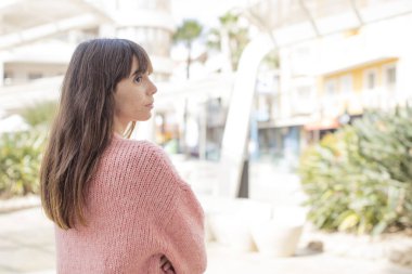 Profil görünümündeki güzel genç kadın ileriyi kopyalamak istiyor, düşünüyor, hayal ediyor ya da hayal kuruyor.