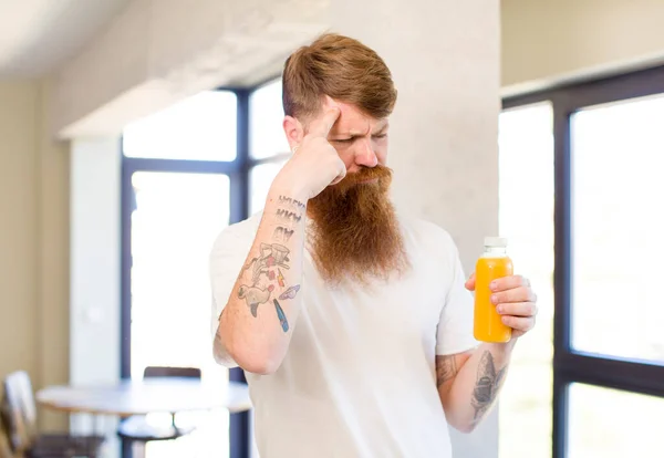 红头发的男人看上去很惊讶 他用橙汁瓶实现了一个新的想法 想法或概念 — 图库照片