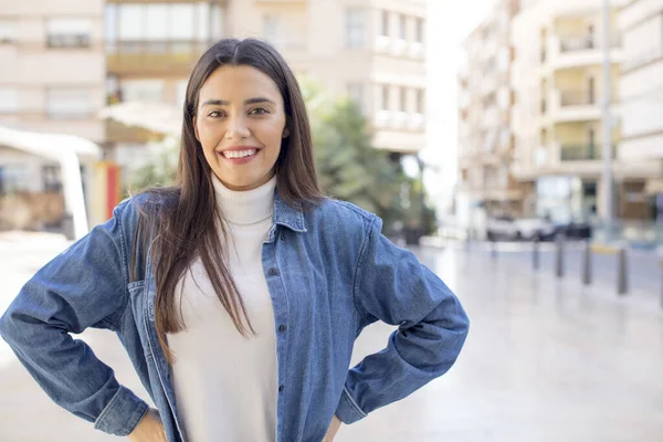 stock image pretty young adult woman smiling happily with a hands on hip and confident, proud and friendly attitude