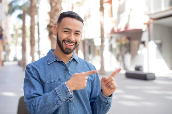 Genç Yakışıklı Adam Neşeyle Gülümsüyor Bir Objeyi Göstererek Veya Reklamını — Stok fotoğraf