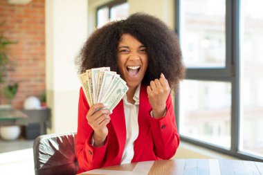Oldukça afro siyahi bir kadın kızgın, sinirli ve sinirli görünüyor. Dolar banknotları konsepti
