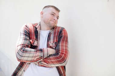 Yakışıklı adam omuz silkiyor, şaşkın ve kararsız hissediyor, kolları bağlı ve şaşkın bir şekilde şüpheye düşüyor.