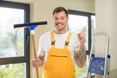 Neşeli bir şekilde gülümsüyor, mutlu hissediyor ve bir tarafı işaret ediyor. pencere temizleme konsepti