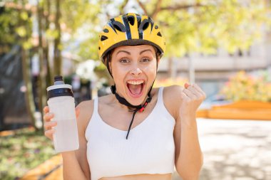 Genç ve güzel bir kadın şokta, gülüyor ve başarıyı kutluyor. bisiklet kaskı konsepti