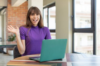 Genç ve güzel bir kadın inanılmaz bir şey karşısında kendini mutlu ve şaşkın hissediyor. masaüstü dizüstü konsepti