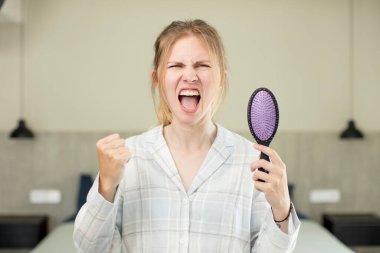 Genç ve güzel bir kadın sinirli, sinirli ve sinirli görünüyor. saç tarağı konsepti