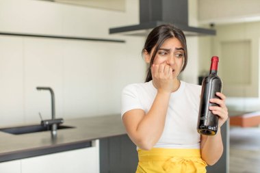 Genç bir kadın korkmuş, endişeli ya da kızgın hissediyor ve bir tarafa bakıyor. şarap şişesi konsepti