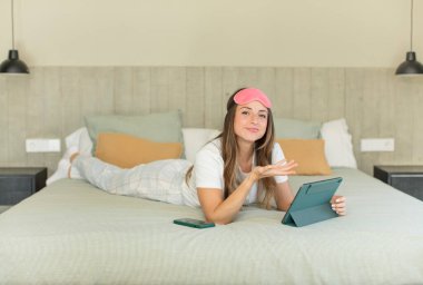 Güzel bir kadın neşeyle gülümser, mutlu hisseder ve bir konsept gösterir. Gece elbisesi ve yatak odası konsepti