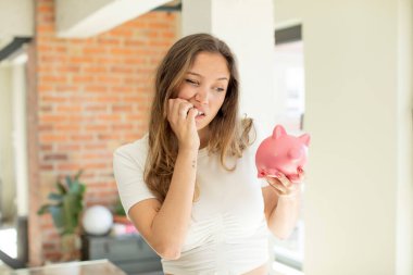 Güzel bir kadın korkmuş, endişeli ya da kızgın hisseder ve yana bakar. Domuz kumbarası konsepti