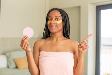 Siyah afro kadın neşeyle gülümsüyor, mutlu hissediyor ve bir tarafı işaret ediyor. güzellik konsepti