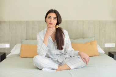 Mutlu, kendinden emin ve elleri çenesinde gülümseyen genç bir manken. dinlenme ve gecelik konsepti