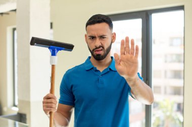 Genç adam ciddi görünüyor. Avuç içi gösteriyor. Durma hareketi yapıyor. pencere temizleme konsepti