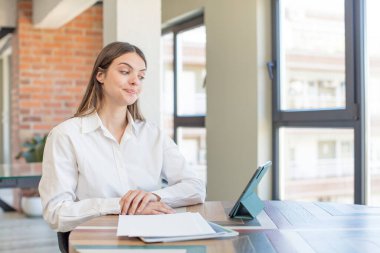 Genç ve güzel bir kadın gülümsüyor ve kendine güveni tam bir ifadeyle bakıyor. Evden işe dolaşma kavramı