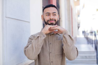 Genç yakışıklı adam düşünceli, meraklı ya da hayal kuruyor, hayal kuruyor ve mekanı kopyalamak için yukarı bakıyor.