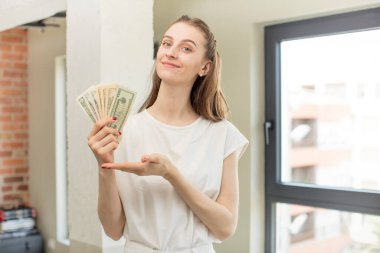 Neşeli bir şekilde gülümsemek, mutlu olmak ve bir konsept göstermek. Dolar banknotları konsepti