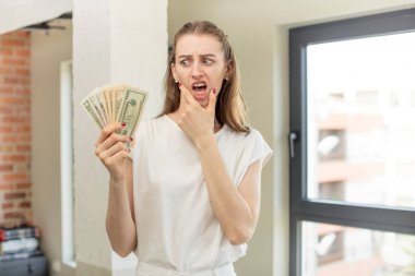 Ağzı ve gözleri açık ve elleri çenesinde. Dolar banknotları konsepti