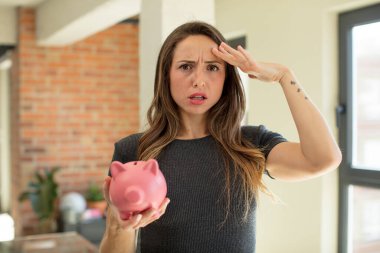 Güzel kadın mutlu, şaşkın ve şaşırmış görünüyor. Domuz kumbarası