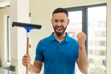 Genç yetişkin bir adam şokta, gülüyor ve başarıyı kutluyor. pencere temizleme konsepti