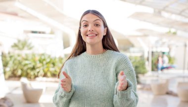 young pretty woman holding an object with both hands on copy space, showing, offering or advertising an object