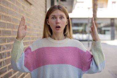 Güzel genç bir kadın iki eliyle bir nesneyi tutuyor, bir nesneyi gösteriyor, sunuyor ya da reklamını yapıyor.