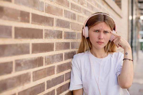 stock image young pretty woman looking surprised, realizing a new thought, idea or concept. headphones and music concept