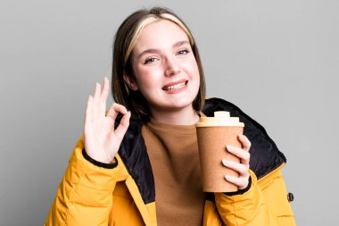 young pretty woman with a coat and a take away coffee