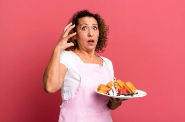 Orta yaşlı güzel bir kadın ellerini havaya kaldırarak çığlık atıyor. Ev yapımı waffle konsepti