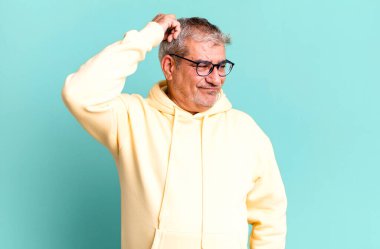 Orta yaşlı bir adam şaşkın ve kafası karışmış hissediyor. Kafasını kaşıyor ve yan tarafa bakıyor.