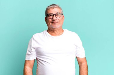 Orta yaşlı, kendinden emin gülümseyen, tatmin olmuş, arkadaş canlısı ve mutlu görünen bir adam.