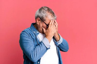 Orta yaşlı bir adam üzgün, hayal kırıklığına uğramış bir bakışla gözlerini kapatıyor. Ağlıyor, yan gözle bakıyor.