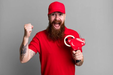 Uzun sakallı adam şok olmuş hissediyor, gülüyor ve başarıyı kutluyor. kargo paketleme konsepti