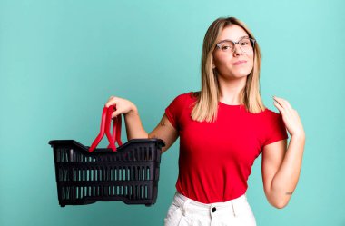 young pretty woman looking arrogant, successful, positive and proud. empty shopping basket concept