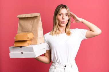 Genç ve güzel bir kadın mutlu, şaşkın ve şaşırmış görünüyor. Yemek teslimatı ve paket servis.