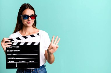 Genç, güzel bir bayan gülümsüyor ve arkadaş canlısı görünüyor, üç numarayı gösteriyor. Sinema filmi veya film konsepti