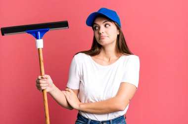 Genç, güzel bir kadın omuz silkiyor, kafası karışık ve kararsız. Pencere temizleme kavramı