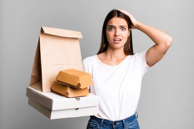 Genç ve güzel bir kadın gergin, endişeli ya da korkmuş hissediyor. Elleri başının üstünde. teslimat ve paket konsepti