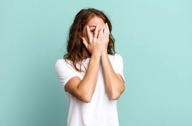 Genç, güzel bir kadın korkmuş ya da utanmış hissediyor. Gözleri yarı kapalı ya da ellerle dikizliyor.